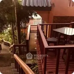 Charming outdoor terrace with lush greenery and wooden deck, perfect for relaxation.
