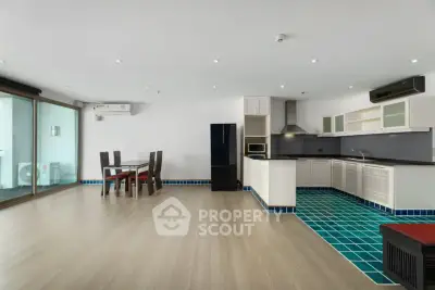 Spacious open-plan living room with modern kitchen and dining area, featuring sleek flooring and stylish decor.