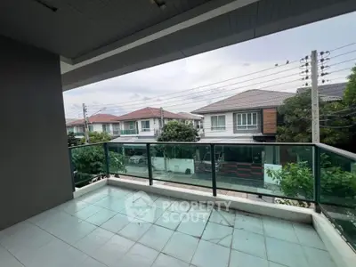 Spacious balcony with glass railing offering a serene neighborhood view