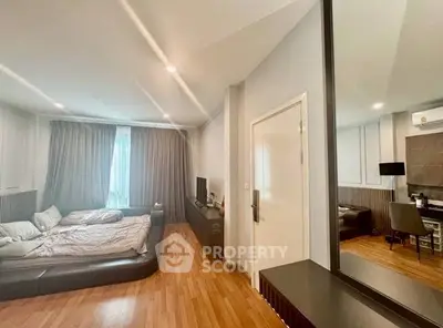Spacious bedroom with modern decor and wooden flooring, featuring a cozy bed and ample natural light.