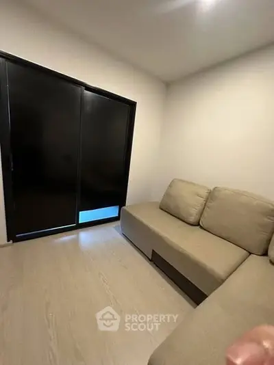 Cozy minimalist living room with sleek black sliding doors and beige sectional sofa.