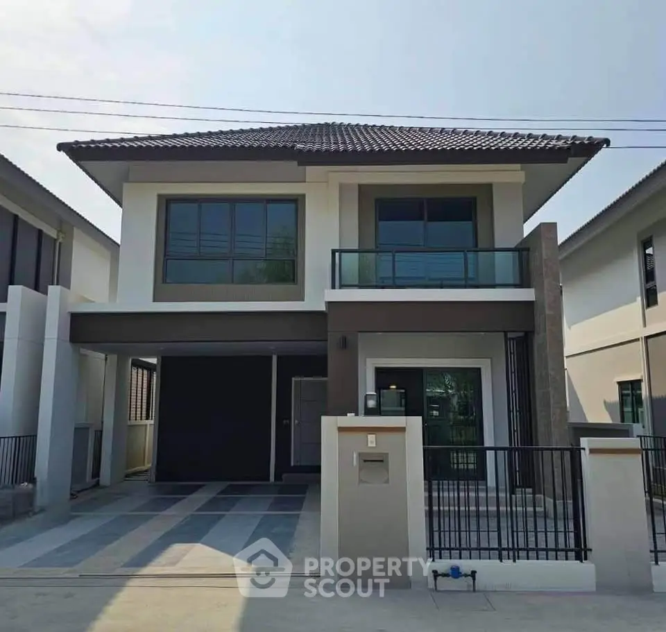Modern two-story house with sleek design and spacious driveway in a suburban neighborhood.
