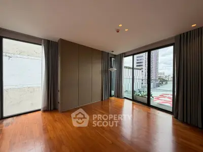 Spacious modern living room with floor-to-ceiling windows and wooden flooring in urban apartment.