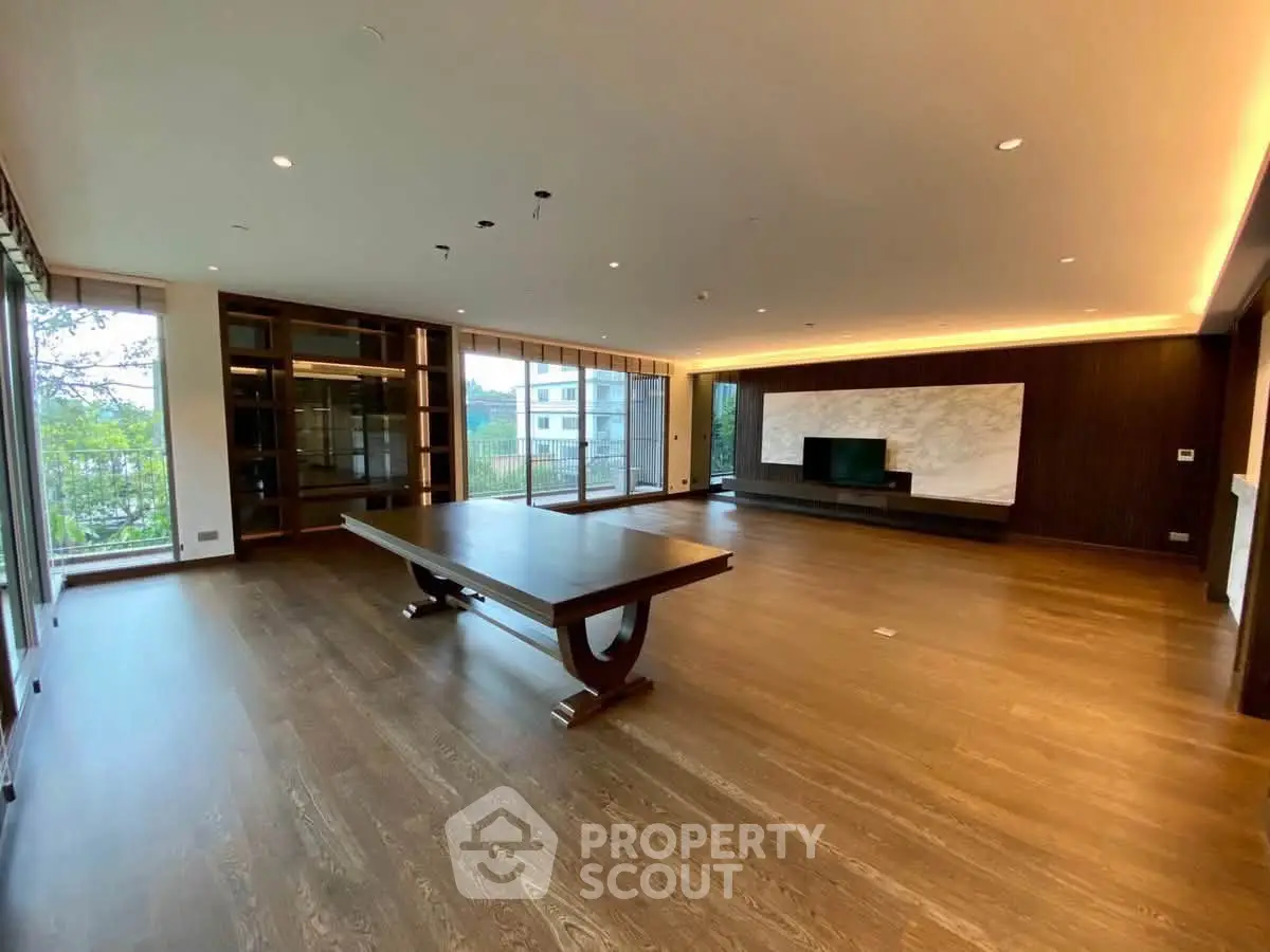 Spacious modern living room with large windows and elegant wooden flooring.
