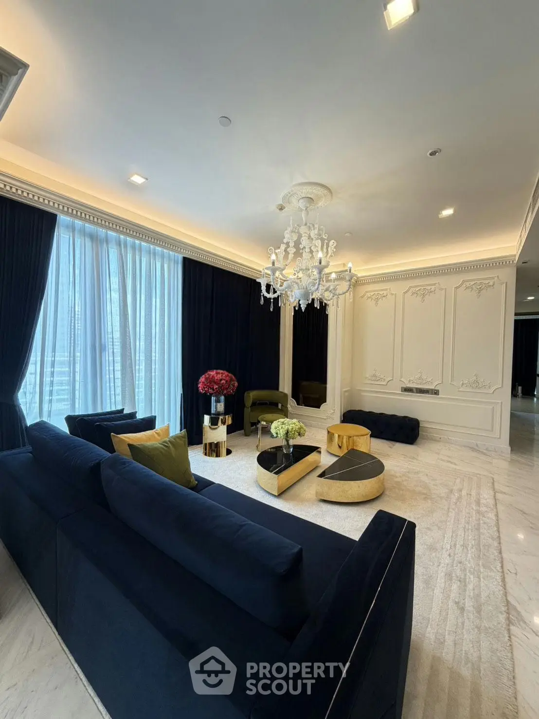 Luxurious living room with elegant chandelier and plush navy sofas in a sophisticated setting.