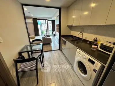 Modern apartment with open kitchen and living room, featuring washing machine and stylish decor.