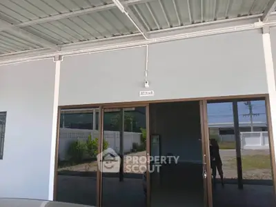 Modern building entrance with glass doors and covered parking area.