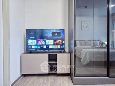 Modern living room with sleek TV setup and view into cozy bedroom