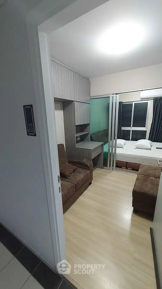 Modern studio apartment with cozy living area and bedroom, featuring sleek wooden flooring and contemporary furnishings.