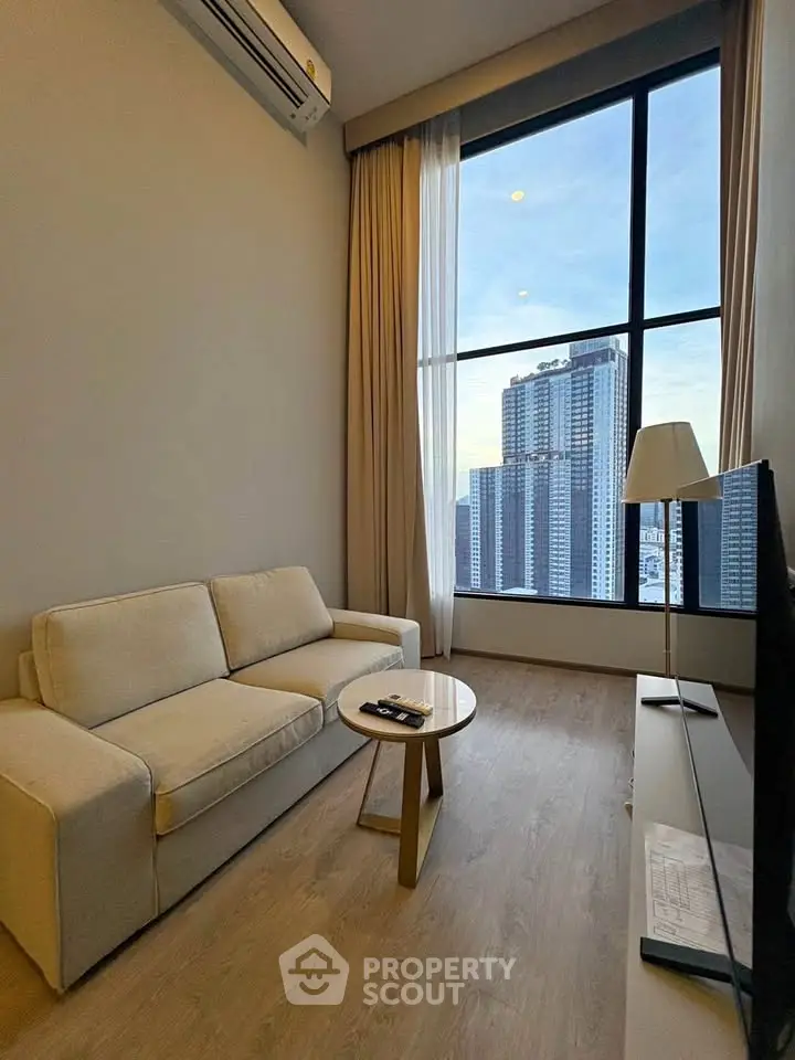 Modern living room with large window and city view, featuring cozy sofa and sleek decor.
