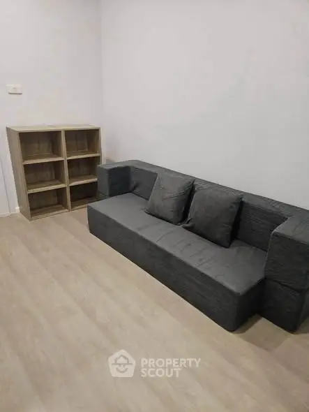 Modern minimalist living room with sleek gray sofa and wooden bookshelf, perfect for cozy urban living.