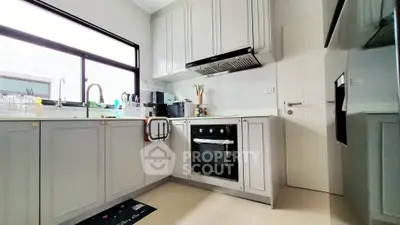 Modern kitchen with sleek cabinetry and built-in oven, featuring ample natural light and contemporary design.