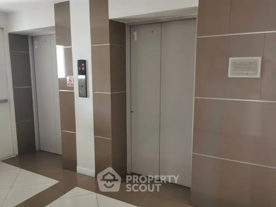 Modern elevator lobby with sleek design and tiled flooring in a residential building.