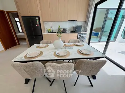Modern dining area with elegant table and chairs, open layout kitchen, and large glass doors.