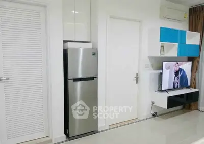 Modern living room with sleek design, featuring a stainless steel fridge and wall-mounted TV for stylish urban living.