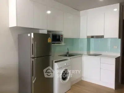 Modern kitchen with sleek white cabinets, stainless steel fridge, and built-in appliances.