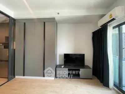 Modern living room with sleek TV stand and air conditioning, featuring floor-to-ceiling windows for natural light.