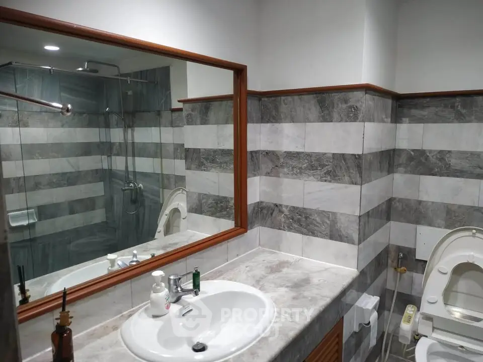 Modern bathroom with marble countertop and large mirror in stylish apartment.
