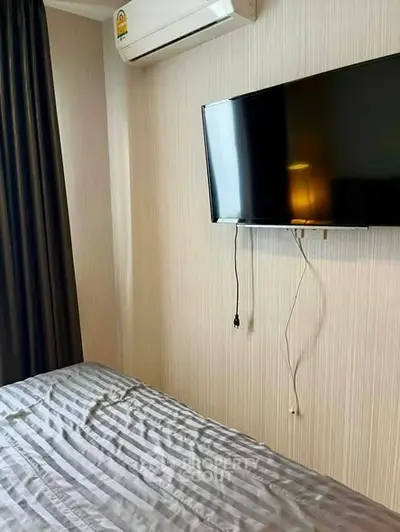 Modern bedroom with wall-mounted TV and air conditioning unit, featuring sleek design and cozy ambiance.
