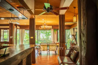 Charming rustic living room with wooden beams and lush garden view.