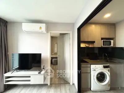 Modern apartment interior with living room and kitchen featuring washing machine and microwave.