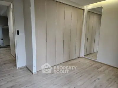 Spacious modern bedroom with sleek wooden flooring and built-in wardrobe