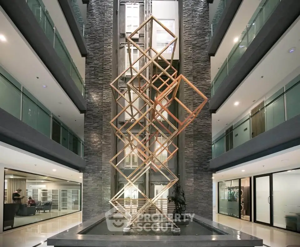 Modern building interior with artistic sculpture and glass balconies, showcasing luxury and elegance.