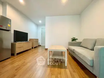 Modern living room with wooden flooring, cozy sofa, and sleek TV setup.
