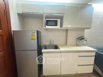 Modern kitchen with sleek cabinetry, stainless steel fridge, and built-in microwave in a compact layout.