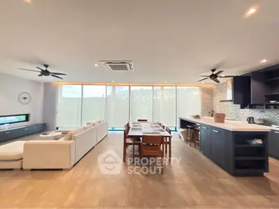 Spacious modern living room with open kitchen and dining area, featuring sleek design and ample natural light.