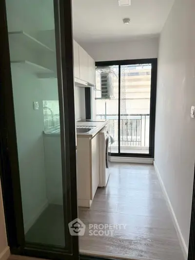 Compact kitchen with balcony view and modern appliances in urban apartment