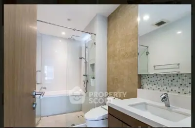 Modern bathroom with glass shower, bathtub, and stylish vanity in a contemporary apartment.