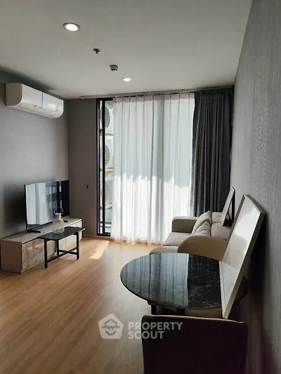 Modern living room with natural light, sleek furniture, and air conditioning in a stylish apartment.