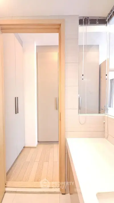 Modern bathroom with sleek design and wooden accents, featuring a bathtub and ample natural light.