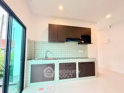 Modern kitchen with sleek cabinetry and tiled backsplash, featuring a large window for natural light.