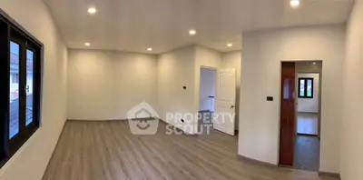 Spacious empty room with wooden flooring and recessed lighting