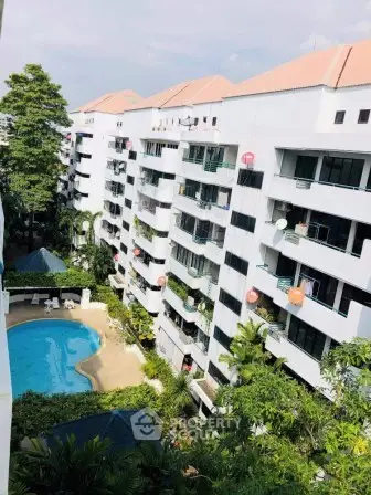Stunning aerial view of modern apartment complex with pool and lush greenery.