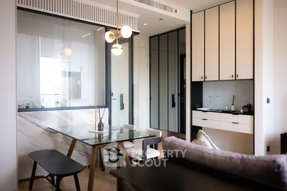 Modern dining area with glass table and stylish lighting in open-plan apartment.