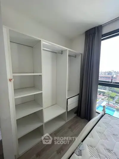 Spacious bedroom with built-in closet and large window offering a stunning view of the cityscape.