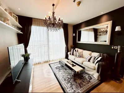 Luxurious living room with elegant chandelier and large mirror, featuring floor-to-ceiling windows and stylish decor.