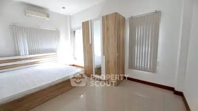 Spacious bedroom with modern wooden furniture and ample natural light.