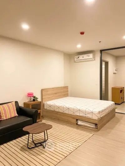 Modern studio apartment with cozy bed, stylish sofa, and sleek wooden furniture.