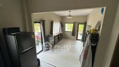 Spacious living room with large windows and balcony access, featuring modern decor and natural light.