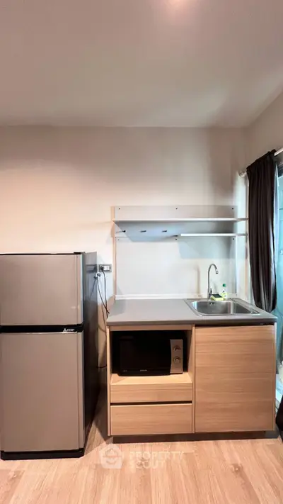 Modern kitchen with sleek fridge and microwave in compact open layout