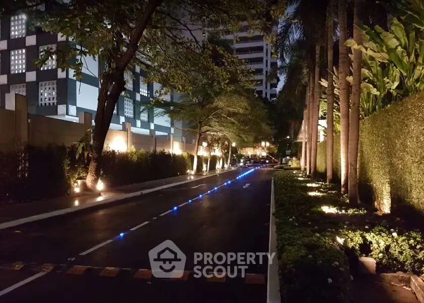 Luxurious residential entrance with illuminated pathway and lush greenery at night.