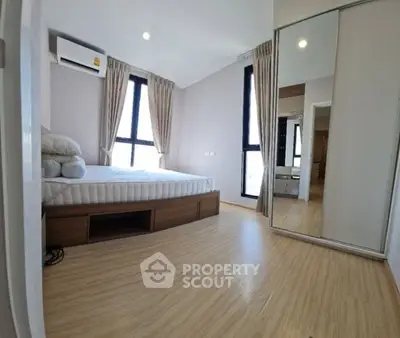 Spacious bedroom with large windows and mirrored closet in modern apartment.