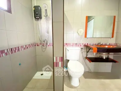 Modern bathroom with shower, toilet, and stylish sink in a tiled setting.