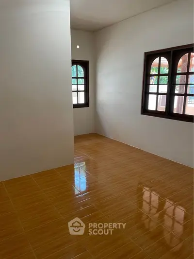 Spacious and bright unfurnished living room with polished terracotta tiles and charming arched windows inviting ample natural light.