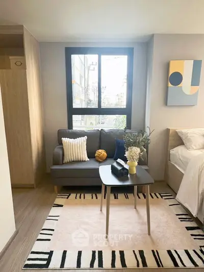 Cozy modern bedroom with stylish decor and natural light, featuring a comfy sofa and chic artwork.