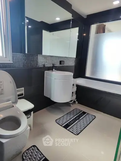 Modern bathroom with sleek design, featuring a bathtub and stylish fixtures.